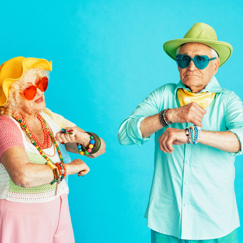Beautiful senior old couple wearing fancy party clothes acting in studio on a colored background. Conceptual image about third age and seniority, old people feeling young inside.