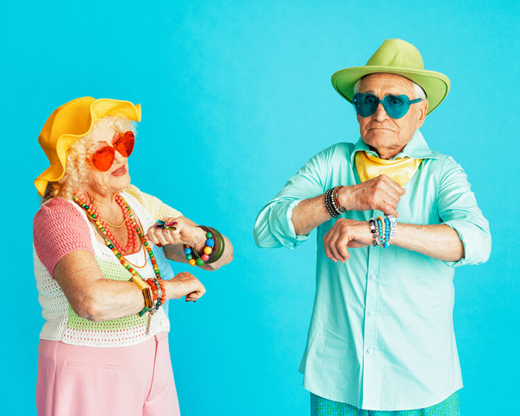 Beautiful senior old couple wearing fancy party clothes acting in studio on a colored background. Conceptual image about third age and seniority, old people feeling young inside.
