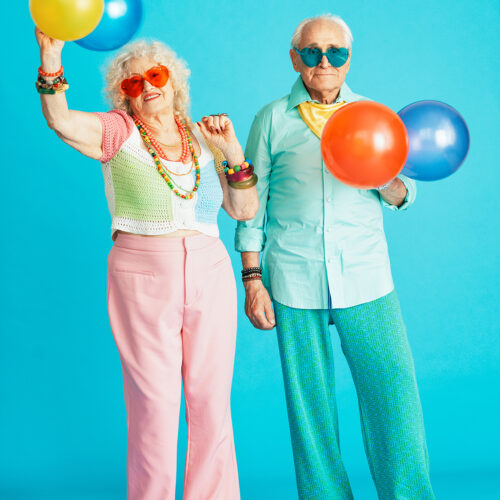 Beautiful senior old couple wearing fancy party clothes acting in studio on a colored background. Conceptual image about third age and seniority, old people feeling young inside.