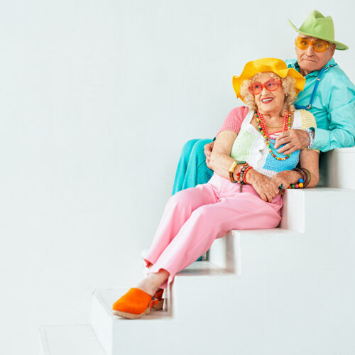 Beautiful senior old couple wearing fancy party clothes acting in studio on a colored background. Conceptual image about third age and seniority, old people feeling young inside.