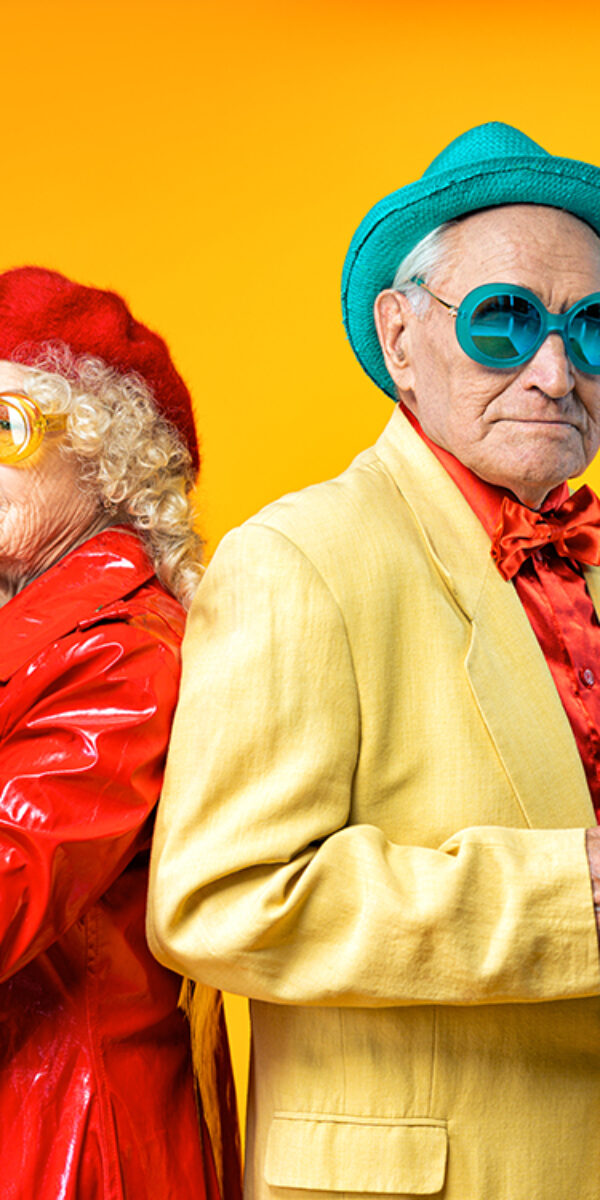 Beautiful senior old couple wearing fancy party clothes acting in studio on a colored background. Conceptual image about third age and seniority, old people feeling young inside.