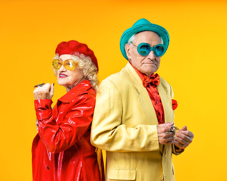 Beautiful senior old couple wearing fancy party clothes acting in studio on a colored background. Conceptual image about third age and seniority, old people feeling young inside.