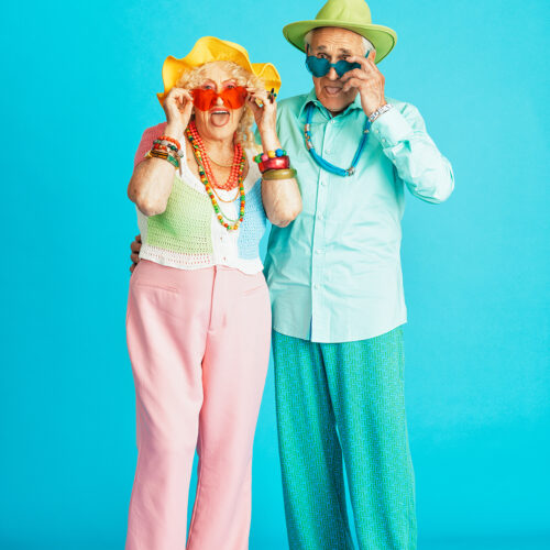 Beautiful senior old couple wearing fancy party clothes acting in studio on a colored background. Conceptual image about third age and seniority, old people feeling young inside.