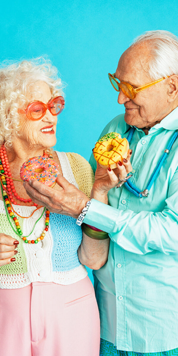 Beautiful senior old couple wearing fancy party clothes acting in studio on a colored background. Conceptual image about third age and seniority, old people feeling young inside.