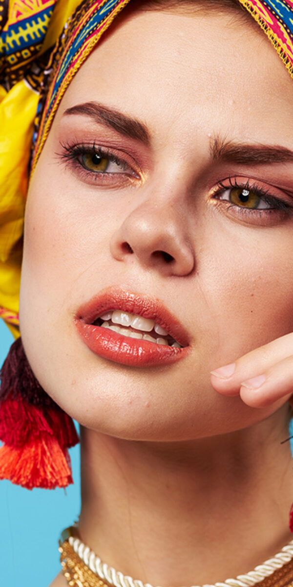 cheerful woman ethnicity multicolored headscarf makeup glamor blue background. High quality photo