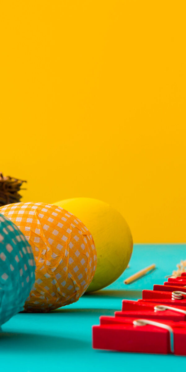 Colorful Easter eggs on blue table with yellow background