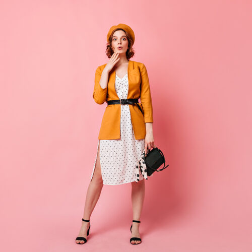 Full length view of jocund french lady with handbag. Studio shot of trendy slim girl in yellow beret.