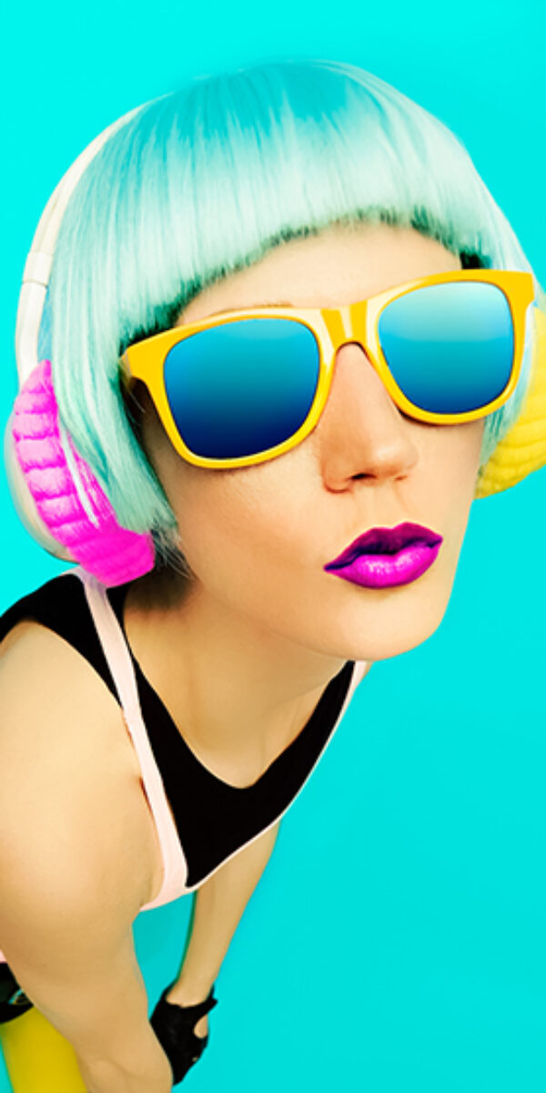 Glamorous party dj girl in bright clothes on a blue background listening to Music.