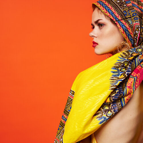 pretty woman in multicolored turban attractive look Jewelry red background. High quality photo