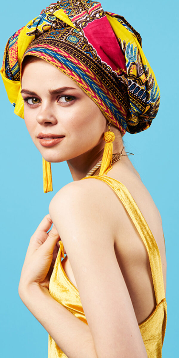 pretty woman in multicolored turban attractive look Jewelry smile blue background. High quality photo