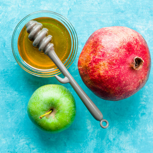 Jewish New Year apple, pomegranate and honey on a turquoise table horizontal