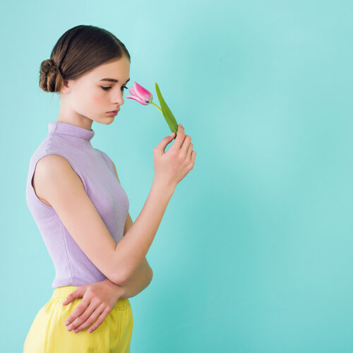 tender teen girl posing with tulip flower, isolated on turquoise