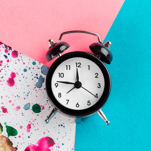 Vintage alarm clock on a creative colorful background with paint sprinkles