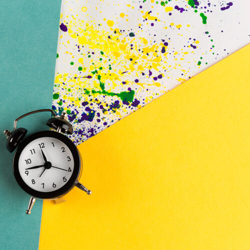 Vintage alarm clock on a creative colorful background with paint sprinkles
