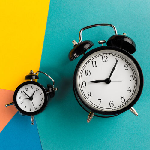 Vintage black alarm clock on a color block background