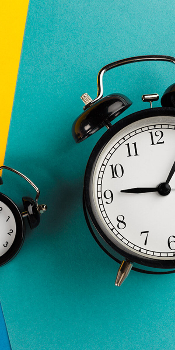 Vintage black alarm clock on a color block background